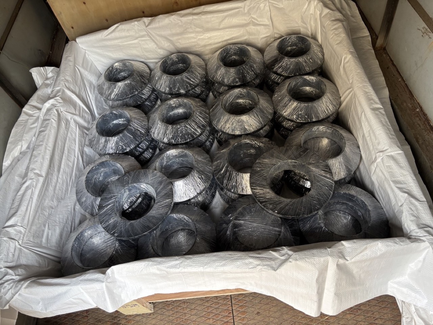 Black-coated ASTM A182 F91 alloy steel weld neck flanges wrapped in a lined wooden export crate — Tesco Steel & Engineering