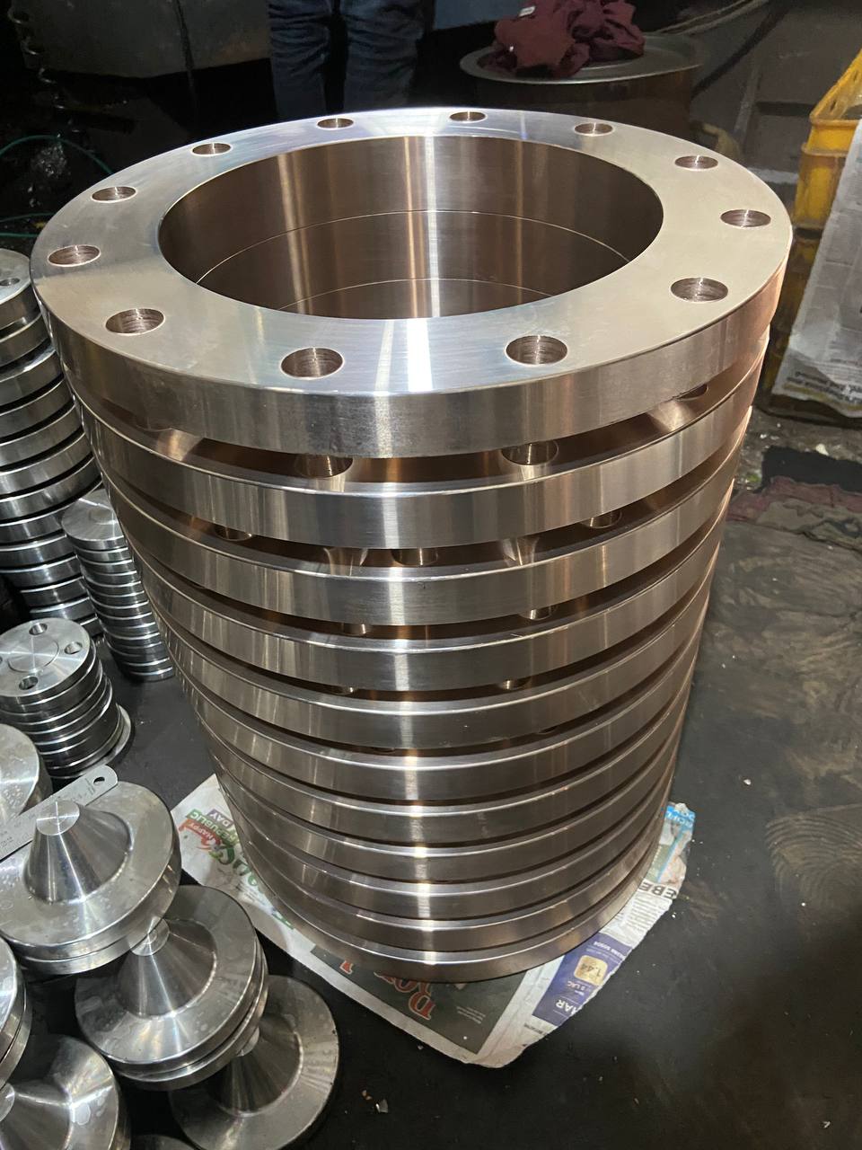 Stack of machined Cupro Nickel 90/10 weld neck flanges ready for final inspection before export packaging