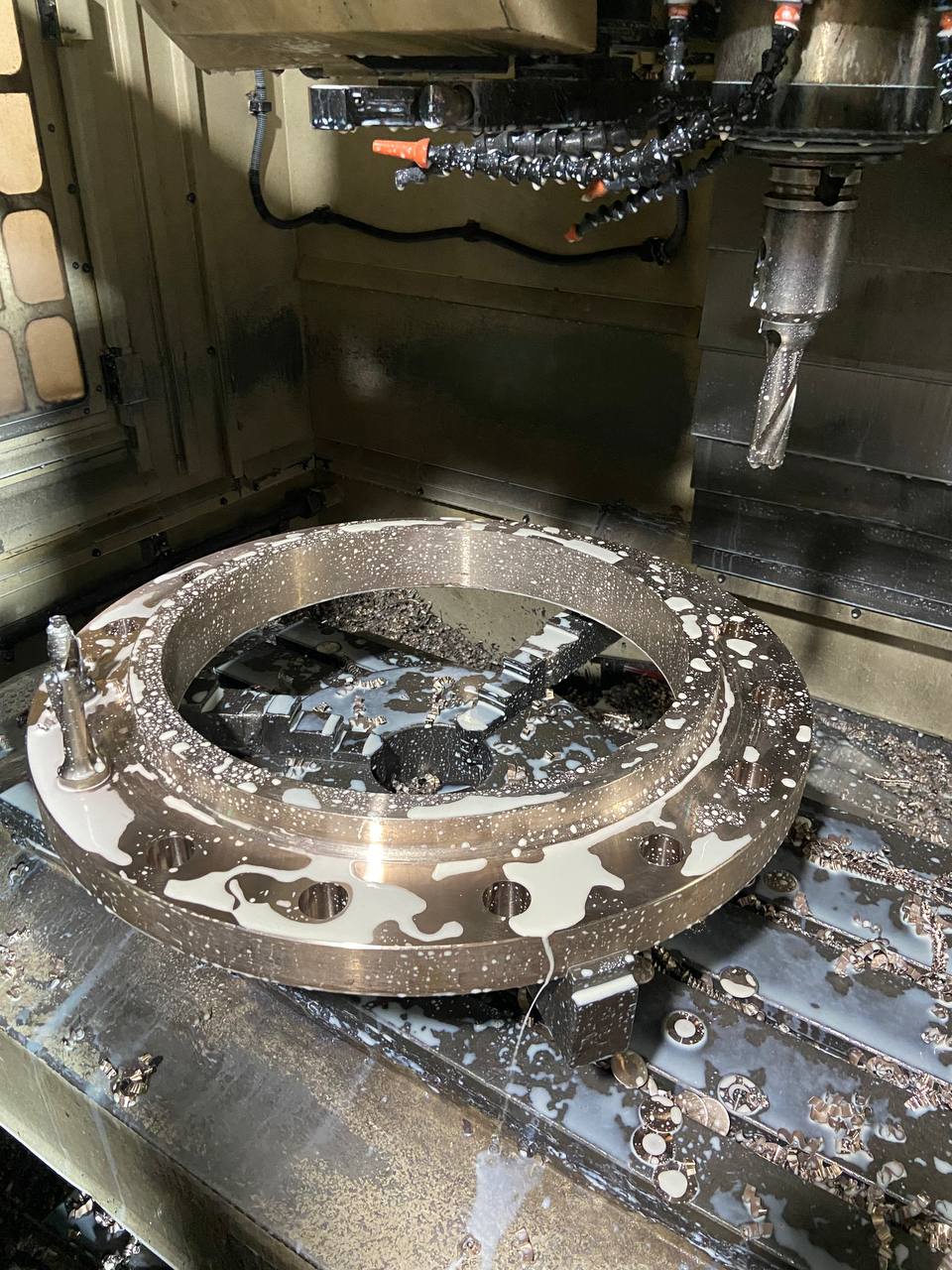 CNC milling of large Cupro Nickel flange on vertical machining centre with coolant flood during manufacturing process