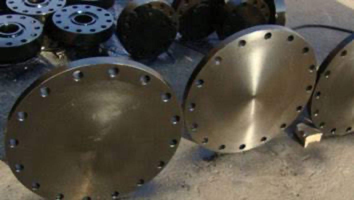 Forged black coated blind flanges of assorted sizes standing at the flange works