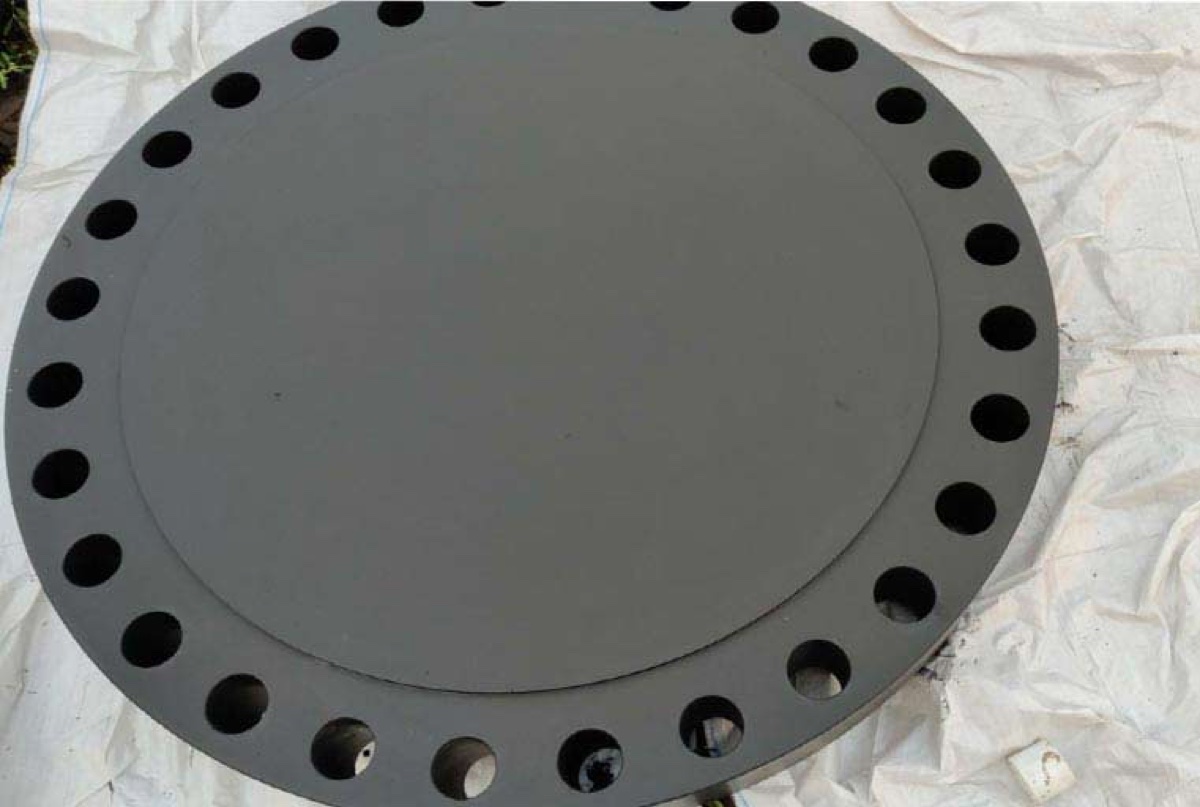 Large diameter grey coated blind flange on protective sheet ready for dispatch