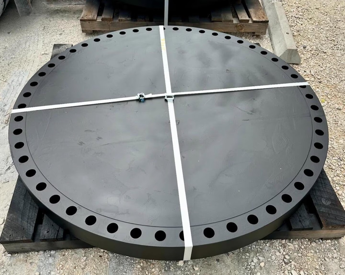 Large diameter black coated blind flange strapped on wooden pallet in the dispatch yard
