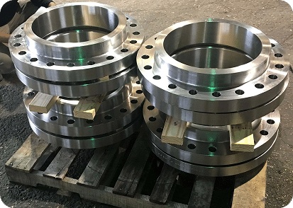 Large nickel alloy flanges stacked on wooden pallet at flange manufacturing works ready for despatch