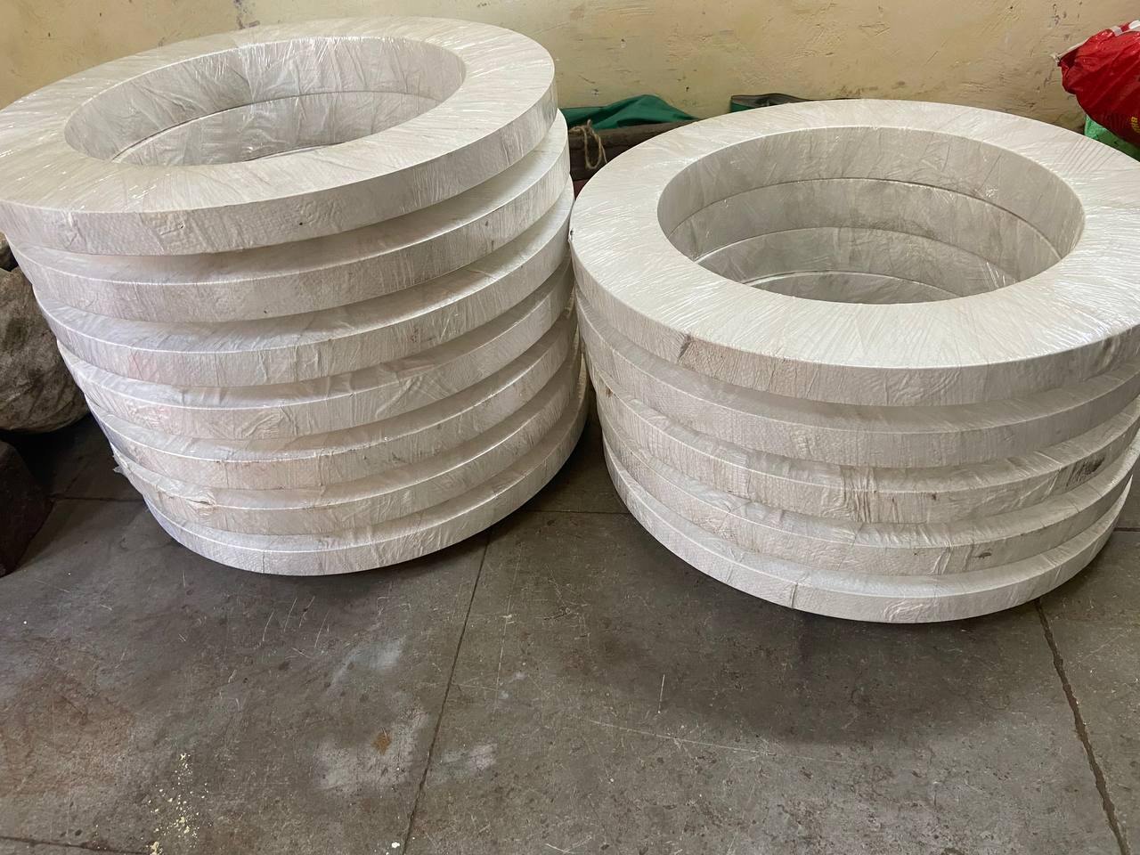 Two large stacks of stainless steel large-diameter flanges individually paper-wrapped ready for international export — Tesco Steel & Engineering Mumbai