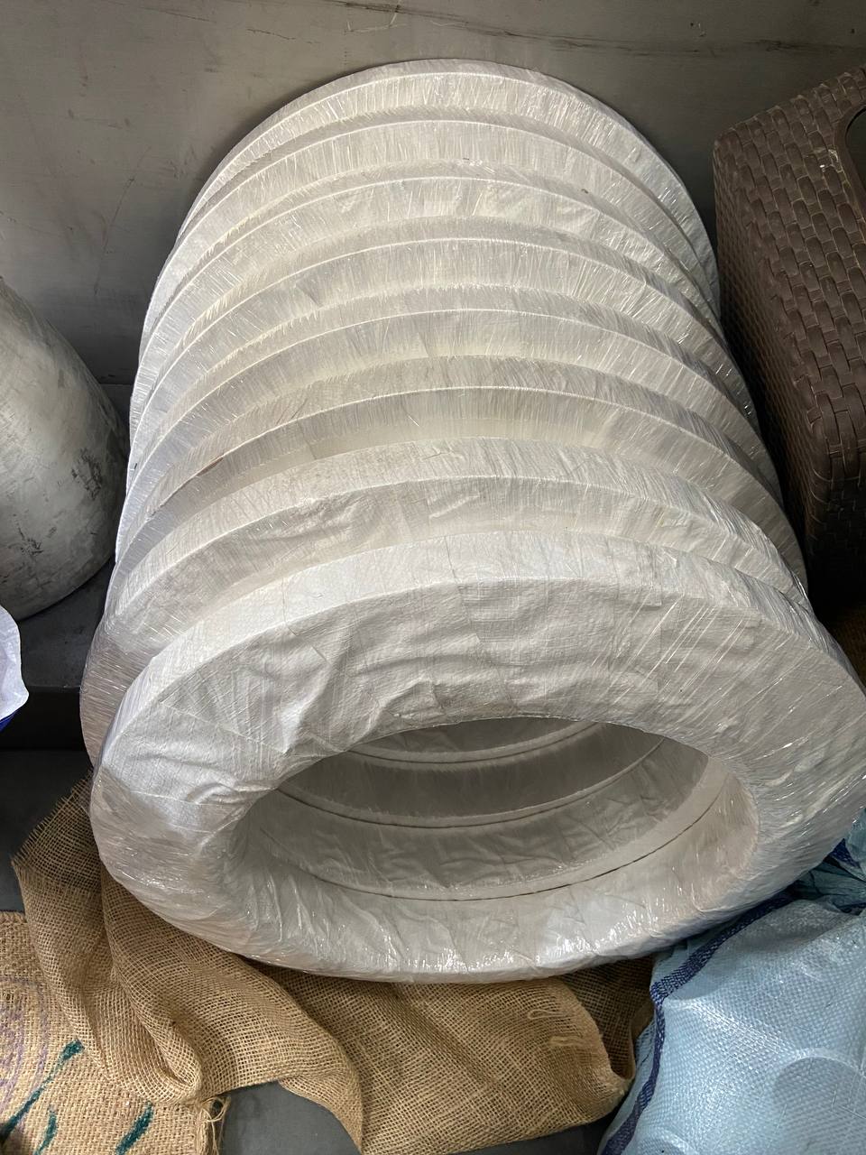 Large diameter stainless steel weld neck flanges stacked and plastic-wrapped in warehouse awaiting export dispatch — Tesco Steel & Engineering