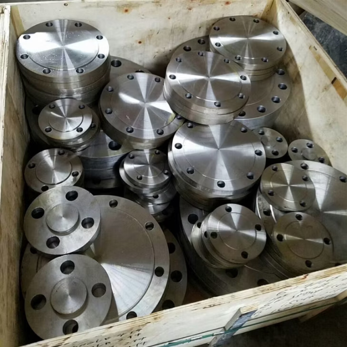 Stainless steel blind flanges of assorted sizes packed in a wooden export crate